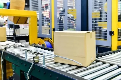 Arqueadora autom�tica em linha realizando o fechamento de caixas com fita de arquear em processo log�stico.