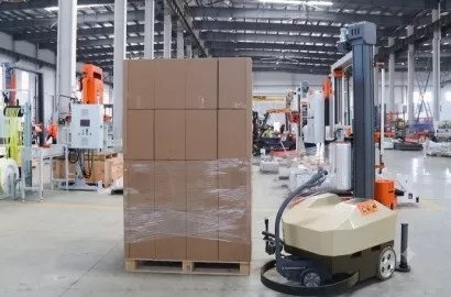 Rob� industrial paletizador envolvendo caixas de papel�o com filme stretch em armaz�m.